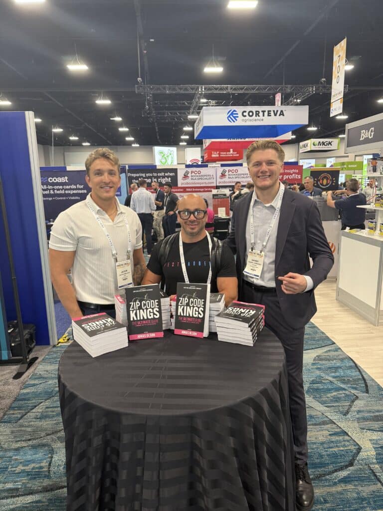 Pest Control Millionaires members at the PestWorld 2025 expo with Zip Code Kings books displayed on the booth table